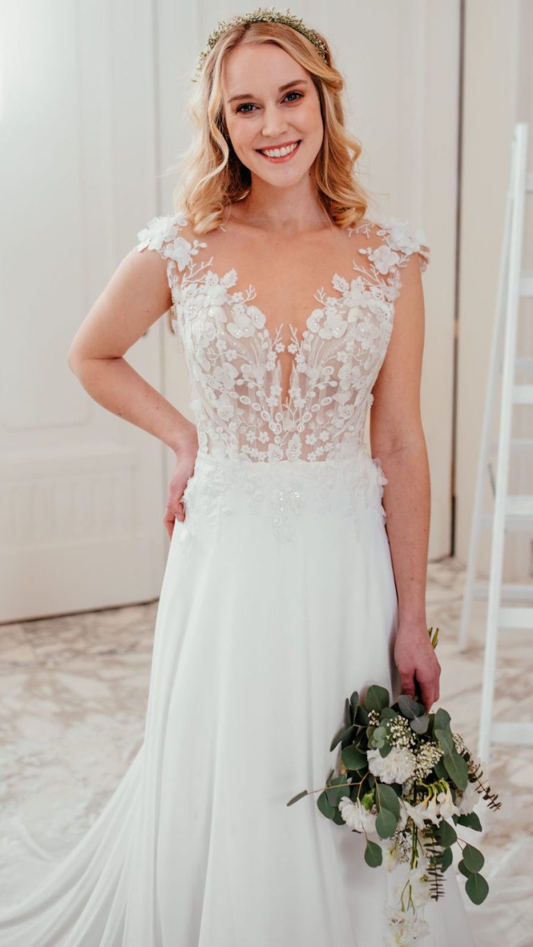 Hochzeitskleid von küsstebraut mit schulterfreien Ärmeln, langer, fließender Silhouette auf mintgrünem Hintergrund.